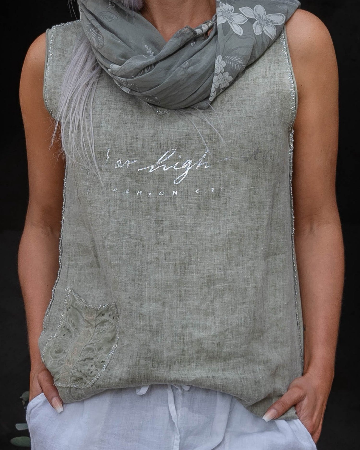 Crafted from 100% linen, this tank style cami offers a breathable, lightweight feel that keeps you cool and comfortable. The silver script detail adds a touch of elegance, while the decorative pocket provides a stylish accent. Finished with silver threading all around, this top exudes subtle glamour, making it ideal for both relaxed days and more polished occasions. Whether paired with your favorite jeans or layered under a jacket, this cami is a versatile piece that adds a refined touch to any outfit